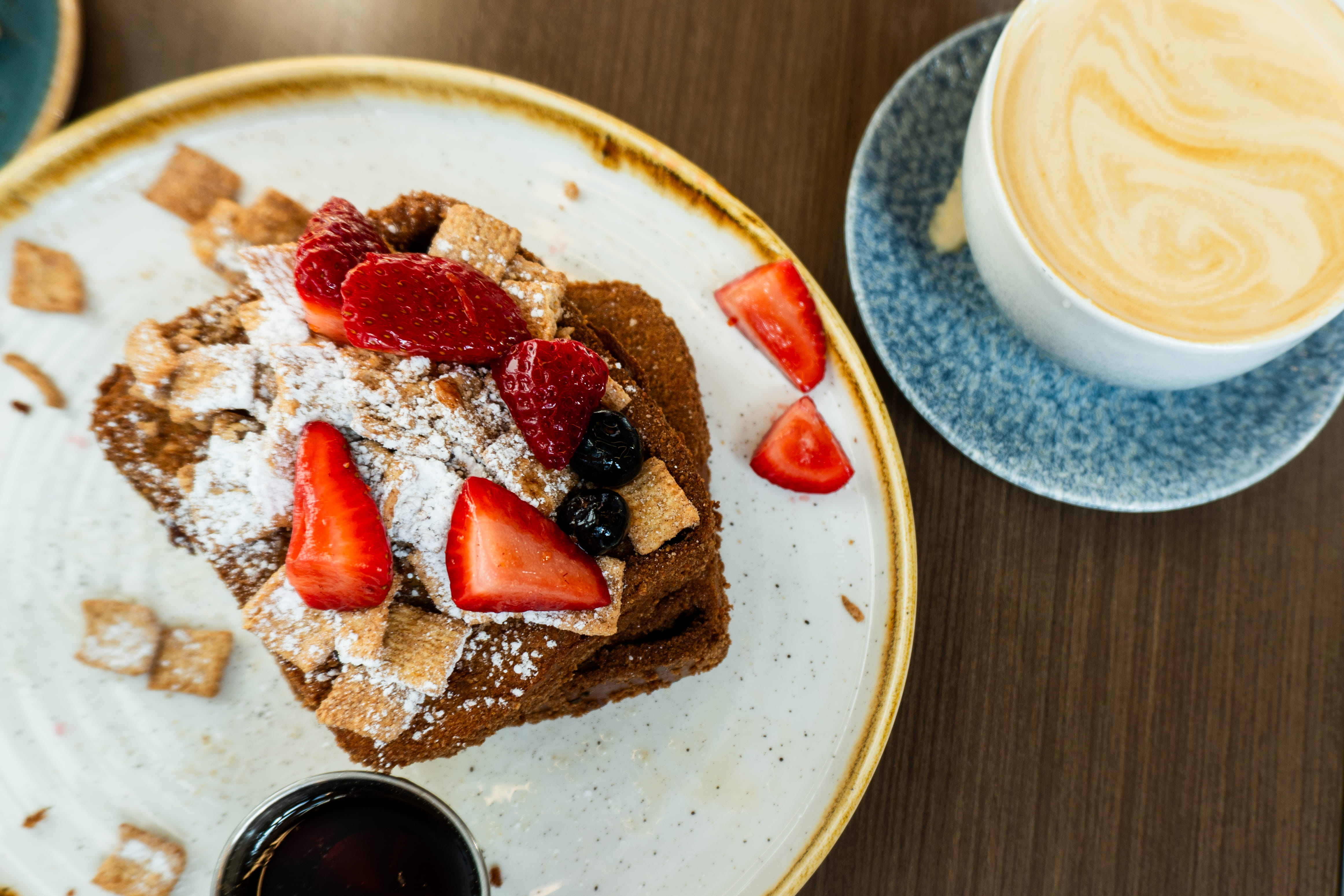 cinnamon crunch french toast topped with berries next to a latte